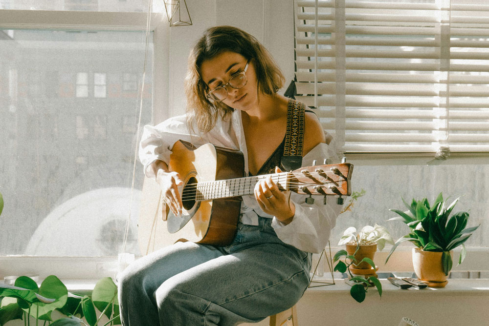 Young woman practicing acoustic guitar in her living room