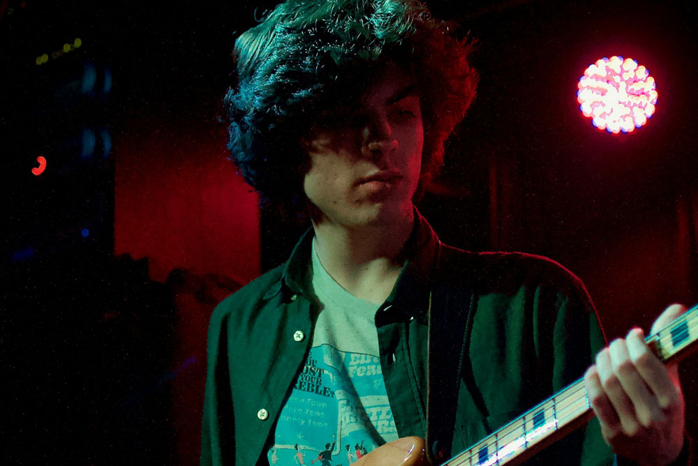 Young man playing electric bass guitar